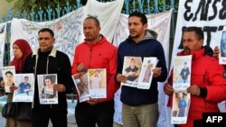 Des familles de personnes originaires d'al-Hansha, disparues en mer lors de tentatives de migration, brandissent des portraits appelant le gouvernement à soutenir les efforts visant à découvrir ce qui est arrivé à leurs proches, Tunis le 6 février 2024. (Photo FETHI BELAID/AFP)