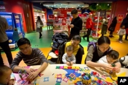 In this Dec. 23, 2017 photo, parents and children play together at an activity station during the grand opening of a Hamleys toy store in Beijing. (AP Photo/Mark Schiefelbein)