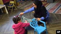 Home visitor Fatema Zamani and her 4-year-old daughter Kaenat build a homemade hammock, imitating a scene from a children's book they just read on April 3, 2024. (Emily Tate Sullivan/EdSurge via AP)