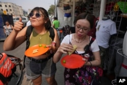 A customer flashes a thumbs up while eating a taco from the Tacos El Califa de León taco stand, in Mexico City, Wednesday, May 15, 2024. Tacos El Califa de León is the first ever taco stand to receive a Michelin star from the French dining guide. (AP Photo/Fernando Llano)