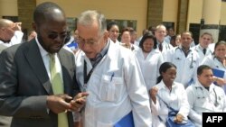 资料照片：肯尼亚基苏木省省长安扬·尼永戈教授（左）与参加位于内罗毕肯尼亚政府学院项目的100名古巴医生之一交谈。（2018年6月11日）