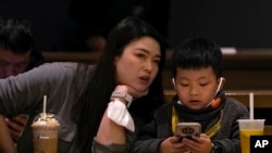 资料照 - 2023年1月19日北京一座咖啡馆里，一位母亲正在和她孩子说话，而儿子却目不转睛地玩着手上的智能手机。