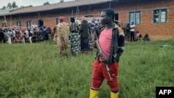 Un milicien de l'Union des patriotes pour la libération du Congo (UPLC) monte la garde dans un bureau de vote à Kalunguta, dans le Nord-Kivu.