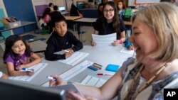 Fifth grade students attend a math lesson with teacher Jana Lamontagne, right, during class at Mount Vernon Community School, in Alexandria, Va., Wednesday, May 1, 2024. (AP Photo/Jacquelyn Martin)