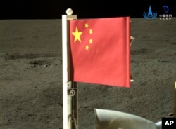 In this China National Space Administration (CNSA) handout image released by Xinhua News Agency, a Chinese national flag carried by the lander of Chang'e-6 probe unfurls at the moon's far side, Tuesday, June 4, 2024. (CNSA/Xinhua via AP)