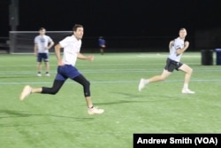 Members of the Carolina Flyers professional men's ultimate frisbee team running and looking up at a frisbee in Chapel Hill, North Carolina on Thursday, April 13, 2023. (VOA/Andrew Smith)