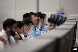 In this photo released by Xinhua News Agency, technical personnel work at the Beijing Aerospace Control Center (BACC) in Beijing, Sunday, June 2, 2024.(Jin Liwang/Xinhua via AP)