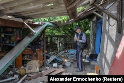 FILE - Local resident Vladimir Odarchenko, 70, stands next to his house damaged during the invasion of the town of Popasna, Ukraine July 14, 2022. (REUTERS/Alexander Ermochenko)
