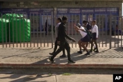 Three high school girls make their way through the city centre on their way to school in Dundee, South Africa, Friday, Oct. 27, 2023. (AP Photo/ Sebabatso Mosamo)