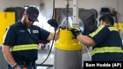 Operators move a used refrigerant cylinder at the A-Gas Rapid Recovery DFW facility on Monday, Oct. 9, 2023, in Arlington, Texas. (AP Photo/Sam Hodde)