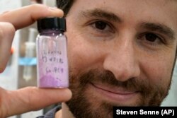 Jarad Mason, assistant professor of chemistry and chemical biology at Harvard University, holds a vile of cobalt-based hybrid material, Thursday, Sept. 14, 2023, in a lab on the school's campus, in Cambridge, Mass. (AP Photo/Steven Senne)