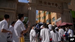 图为2023年6月7日，中国的应届高中毕业生们在一个中学外排长队参加每年一次的“全国高校统一考试”，俗称“高考”，一名警察站在一旁注视着排队的学生。今年全中国有超过120万的高中毕业生参加高考。