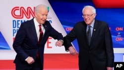 L'ancien vice-président Joe Biden, à gauche, et le sénateur Bernie Sanders, à droite, se saluent avant leur débat dans les studios de CNN à Washington, le dimanche 15 mars 2020. (AP Photo / Evan Vucci)