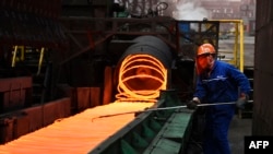 A Chinese employee sorts hot red steel at a steel plant in Zouping in China's eastern Shandong province on March 5, 2018.