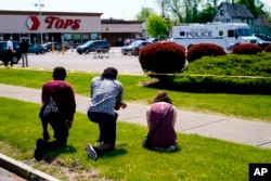 People pray outside the scene of Saturday's shooting at a supermarket, in Buffalo, N.Y., May 15, 2022. The shooting is the latest example of targeted racial violence. (AP Photo/Matt Rourke)