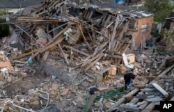 Anna Shevchenko, 35, waters the few flowers that survived in the garden of her home in Irpin, near Kyiv, on Tuesday, May 3, 2022. (AP Photo/Emilio Morenatti)