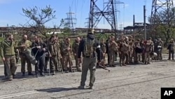 俄罗斯国防部发布的视频截图显示，乌克兰军人从马里乌波尔亚速钢铁厂走出投降，在俄罗斯士兵前站成一排。（2022年5月18日）