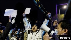 资料图片：2022年11月28日，在新冠病毒疫情持续扩散之际，北京民众为乌鲁木齐火灾遇难者守夜后，举着白纸抗议中共当局的封控限制。