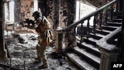 A Russian soldier patrols at the Mariupol drama theater that was bombed last March 16, in Mariupol. This picture was taken during a trip organized by the Russian military on April 12, 2022. (Photo by Alexander NEMENOV / AFP)
