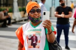 Une supportrice de l'ancien président de la Côte d'Ivoire Laurent Gbagbo prend des photos avec son smartphone à l'aéroport international de Bruxelles, jeudi 17 juin 2021.