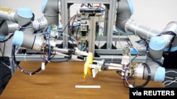 A dual-armed robot picks up a banana and peels it. Image taken December 2, 2021 and released by ISI (Kuniyoshi) Lab., School of Info. Sci & Tech., The University of Tokyo, Japan. (Handout via REUTERS)