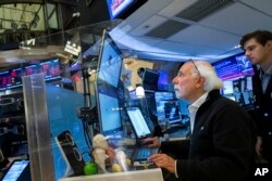 In this photo provided by the New York Stock Exchange, trader Peter Tuchman, seated, works on the floor, June 13, 2022. (Courtney Crow/New York Stock Exchange via AP)