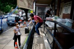 In this June 11, 2020, photo Lourdes Sherby, center, with Guadalupe Family Services, hands diapers to Louisa Peralta in Camden, N.J. “I think we’re received a lot better than we used to be,” said Sgt. Dekel Levy, 41, as he helped hand out diapers.