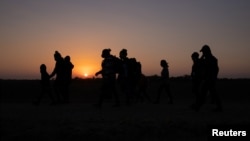 The sun rises as asylum-seeking migrant families from Honduras and El Salvador walk towards the border wall after crossing the Rio Grande River into the United States from Mexico on a raft, in Penitas, Texas.