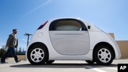 In this May 13, 2015 photo, a reporter walks toward Google's new self-driving car at the Google campus in Mountain View, California. (AP Photo/Tony Avelar)