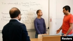 FILE - Teacher George Ferenci (L) listens to Minawar Ahmadzai (R) and Mohammed Salah Uddin Ahmed (C) during an English class for refugees at Paris' Sciences Po university in Paris, France, March 15, 2016. (REUTERS/Philip Wojazer)