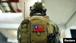 台湾新台北市一名市民背着写有“世界第一，台湾精神”的台湾旗帜的背包参加使用仿真枪的枪击和战斗技能训练。（2022年5月21日）