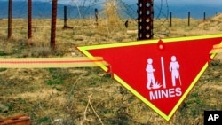 资料照：巴格拉姆空军基地雷场旁悬挂着国际地雷警告标志。（2002年3月22日）