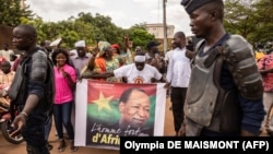 Un homme tient une affiche représentant Blaise Compaoré, ancien président du Burkina Faso, devant l'aéroport de Ouagadougou le 7 juillet 2022 alors qu'ils attendent son retour 8 ans après avoir été contraint à l'exil en Côte d'Ivoire en 2014.