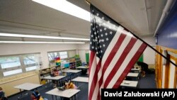 An American flag hangs in a classroom as students work on laptops in a Denver school in Colorado. 