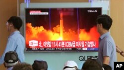 In this Saturday, July 29, 2017 photo, People watch a TV news program showing an image of North Korea's latest test launch of an intercontinental ballistic missile (ICBM), at the Seoul Railway Station in Seoul, South Korea. 