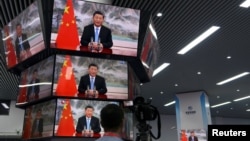 上海举行的中国国际进出口展销会媒体中心的多面电视屏幕播放中国领导人习近平的讲话。（2021年11月4日）