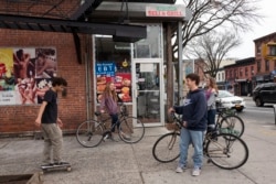 FILE - High school students hang out on a Brooklyn street corner, Friday, March 20, 2020 in New York. The city's public schools are closed due to the coronavirus. (AP Photo/Mark Lennihan)