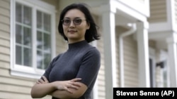 In this Monday, June 15, 2020, photo Xujiao Wang, 32, of East Providence, R.I., stands for a photograph outside her home. Wang works for a Massachusetts company and is on the Optional Practical Training program for student visa holders. (AP Photo/Steven Senne)