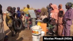 Des femmes et des enfants tirent de l'eau du puits dans le camp Assaga, à Diffa, au Niger, le 3 mars 2016. (VOA/Nicolas Pinault)