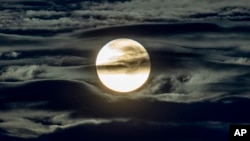 The full moon shines surrounded by clouds in the outskirts of Frankfurt, Germany, early Wednesday, Sept. 2, 2020. 
