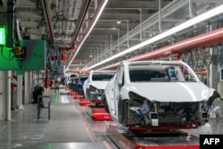 FILE - Cars are seen on the assembly line during a tour of the Tesla Giga Texas manufacturing facility ahead of the "Cyber Rodeo" grand opening party on April 7, 2022 in Austin, Texas. (Photo by SUZANNE CORDEIRO / AFP)