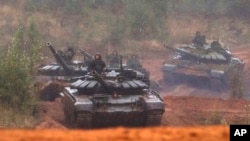 FILE - Russian tanks advance during the Zapad 2017 military exercises near St. Petersburg, Russia, Sept. 18, 2017.
