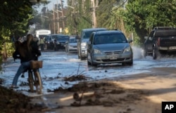 FILE - In this Feb. 10, 2019 file photo, vehicles pass through surf that washed over a roadway on Oahu's north shore near Haleiwa, Hawaii. (Cindy Ellen Russel/Honolulu Star-Advertiser via AP, file)