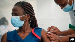 A worker reacts as she receives a shot of AstraZeneca COVID-19 vaccine, manufactured by the Serum Institute of India and provided through the global COVAX initiative, in Machakos, Kenya, Wednesday, March 24, 2021. (AP Photo/Brian Inganga)
