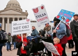 Keagan Nedrow, left, and Reed Nedrow, bottom right, stand with their mother, Tara Nedrow, right, who teaches history at Union High School, and other teachers, during a teacher rally against low school funding in Oklahoma City, Oklahoma. (AP Photo)