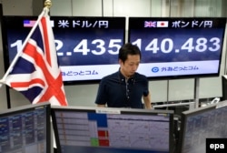 A monitor (R) displays the current exchange rate of the Japanese yen against the British Pound as a trader works at a foreign exchange brokerage in Tokyo, Japan, 24 June 2016.