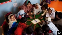 FILE - Pakistani students are seen gathered around their teacher in a classroom in Karachi, Pakistan, Feb. 24, 2014.