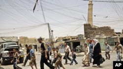 Des habitants passant devant le minaret penché de la mosquée Al-Nouri, le 8 juin 2009, Mossoul, Irak. 