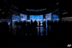 FILE - People look at a display of Samsung screens and products at the CES tech show Tuesday, Jan. 7, 2025, in Las Vegas. (AP Photo/Abbie Parr)