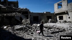 Des gens marchent près de bâtiments détruits dans le quartier de Douma, à Damas, le 4 avril 2017.
